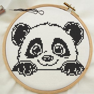 Peut inclure: Broderie au point de croix noir et blanc d'un visage de panda dans un cercle de broderie en bois.