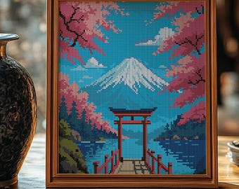 Op de afbeelding: Een ingelijst kruissteekkunstwerk dat een Japans berglandschap met een rode torii-poort en kersenbloesems afbeeldt. De berg is wit met een blauwe lucht en wolken. Het kunstwerk bevindt zich in een houten lijst.
