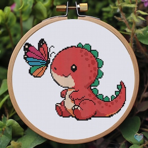 Op de afbeelding: Een rode dinosaurus met een groene staart en een vlinder met kleurrijke vleugels. De dinosaurus zit op een witte achtergrond.