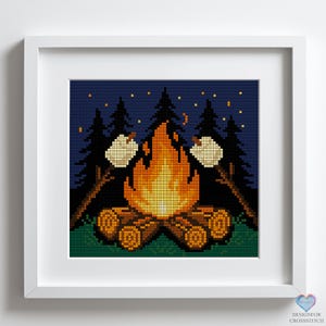 Peut inclure: Un motif de point de croix représentant un feu de camp avec deux guimauves qui rôtissent sur des bâtons devant un ciel nocturne bleu foncé avec des étoiles. Le feu est orange et jaune, et les bûches sont brunes. Les arbres sont vert foncé.