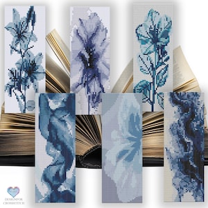 Pode incluir: Seis designs diferentes de marcadores de ponto cruz azul e branco com motivos florais. Os marcadores são exibidos em um fundo de um livro aberto.