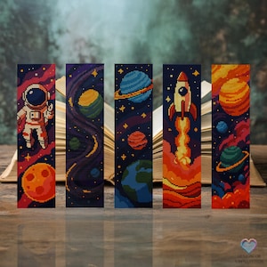 Può includere: Set di cinque segnalibri a tema spaziale con un razzo, un astronauta, pianeti e stelle. I segnalibri sono colorati e pixelati, che ricordano un motivo a punto croce.