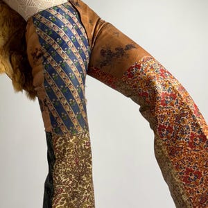 Peut inclure: Un vêtement patchwork avec un mélange de tissus à motifs bleus, marron et rouges. Le design comprend des motifs floraux et rayés, créant une esthétique unique et vintage. Le vêtement semble être un pantalon ou une combinaison.