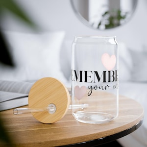Könnte beinhalten: Ein klares, dosenförmiges Trinkglas mit einem Bambusdeckel und Strohhalm. Das Glas zeigt die Worte "REMEMBER your why" in Schwarz und zwei rosa Herzen. Der Deckel ist rund und aus hellem Holz.