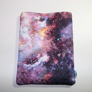 May include: A quilted galaxy print laptop sleeve with a purple button closure. The sleeve has a blue tag with the text "Bloom & Blossom" on it.