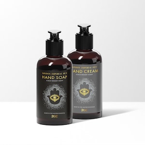 May include: Two brown bottles with black pump tops and labels. The left bottle is labeled "London Imperial Oud Hand Soap" and the right bottle is labeled "London Imperial Oud Hand Cream". Both bottles feature a gold hamsa hand with an eye in the center.
