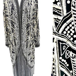 May include: A long, black and white patterned dress with a geometric design. The dress features a V-neck, long sleeves, and a fringe hem. The intricate pattern includes dots, lines, and shapes.