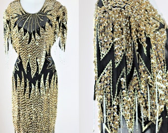 Puede incluir: Un vestido negro y dorado con lentejuelas, manga corta y flecos en el dobladillo. El vestido está cubierto de lentejuelas y cuentas.