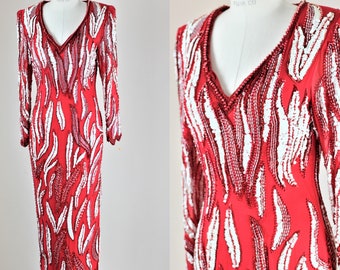 Könnte beinhalten: Ein langärmeliges rotes und weißes Paillettenkleid mit V-Ausschnitt. Das Kleid ist mit einem Muster aus weißen Pailletten auf rotem Grund bedeckt.