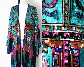 Puede incluir: Una chaqueta larga de lentejuelas negras con un patrón geométrico en tonos turquesa, rosa, naranja y azul. La chaqueta tiene un corte de estilo kimono y está abierta en la parte delantera.