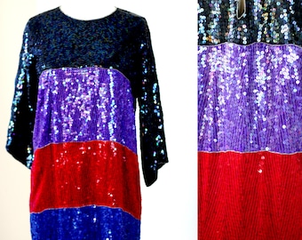 May include: A sequined dress with a black, purple, red, and blue color block pattern. The dress has a round neckline and three-quarter sleeves.