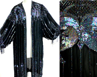 May include: A long black sheer robe with iridescent sequins and fringe. The robe has a V-neck and long sleeves. The sequins are arranged in a geometric pattern.