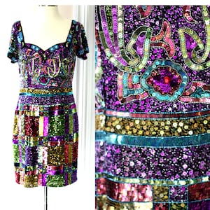 May include: A short, sequined dress with a colorful geometric pattern. The dress has a scoop neckline and short sleeves. The sequins are in shades of purple, green, gold, and red.