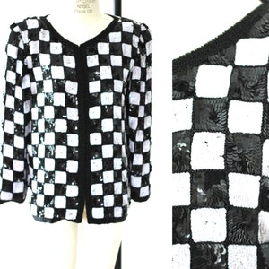 May include: Black and white checkered sequined jacket with a v-neck and long sleeves.