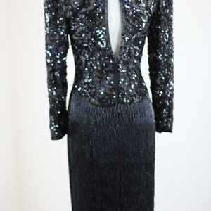 May include: A black sequined long-sleeved dress with a keyhole back and a slit in the skirt.