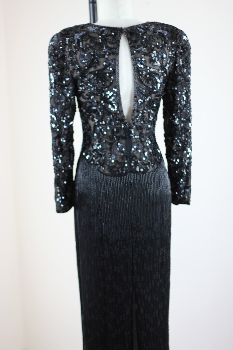May include: A black sequined long-sleeved dress with a keyhole back and a slit in the skirt.