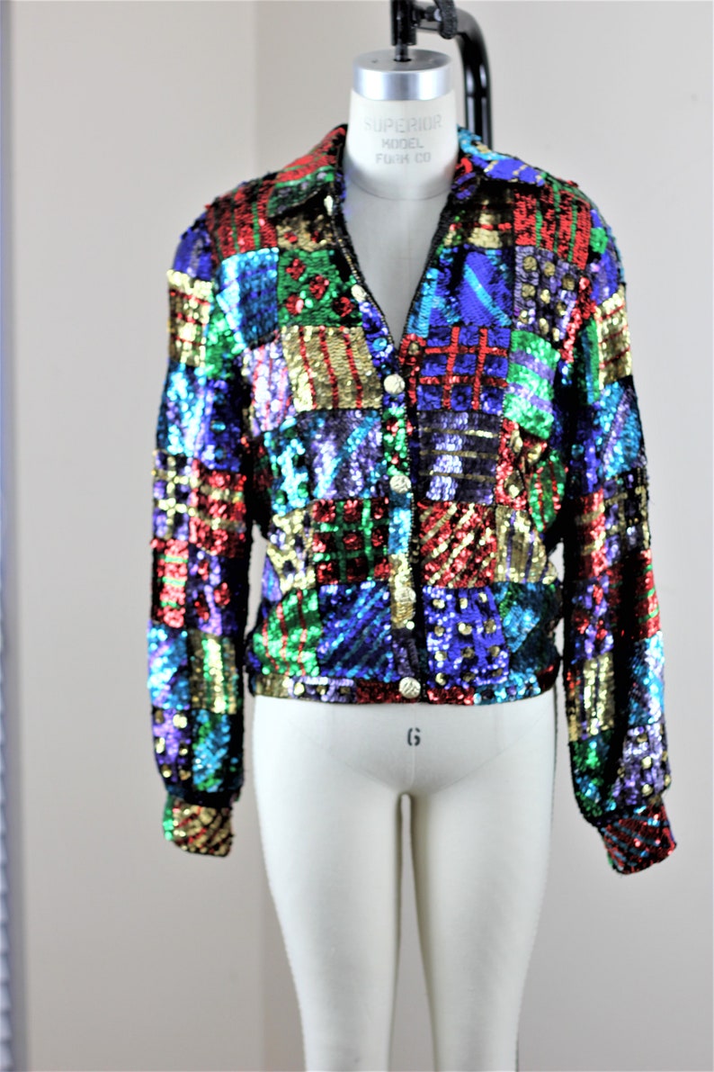 Puede incluir: Chaqueta de lentejuelas colorida con dise&ntilde;o de patchwork. La chaqueta tiene cuello, mangas largas y botones dorados. Las lentejuelas son en tonos rojo, azul, verde y dorado.