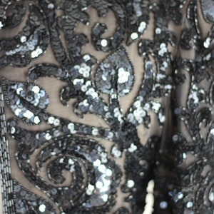 May include: A black sequined top with a floral pattern. The sequins are small and closely spaced, creating a shimmering effect.