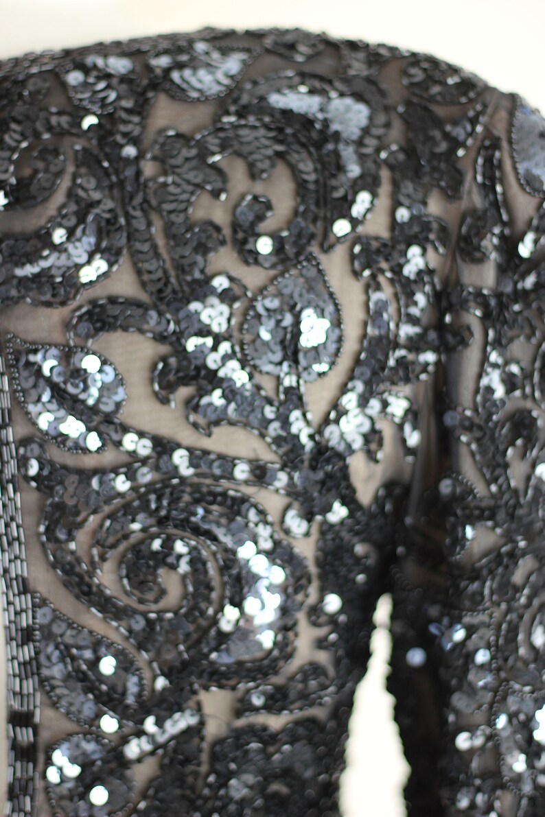May include: A black sequined top with a floral pattern. The sequins are small and closely spaced, creating a shimmering effect.