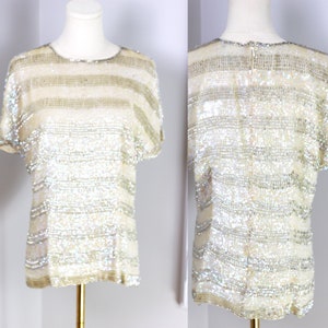 May include: A white sequined top with horizontal stripes. The top has short sleeves and a round neckline.