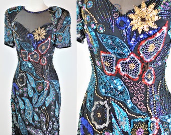 May include: A short-sleeved, black sequined dress with a floral design in shades of blue, red, and gold. The dress has a sheer neckline and is adorned with sequins and beads.
