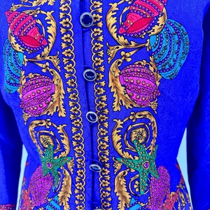 May include: A royal blue jacket with a detailed pattern of seashells, starfish, and ornate gold accents. The jacket features a button-up front with dark blue buttons. The design incorporates shades of pink, teal, and green.