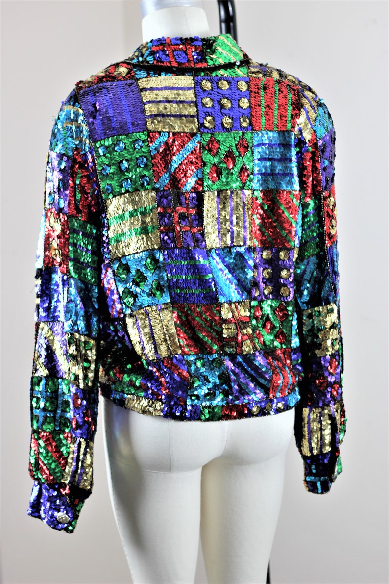 Puede incluir: Chaqueta de lentejuelas colorida con dise&ntilde;o de patchwork. La chaqueta presenta una variedad de colores, incluyendo azul, verde, rojo y dorado. La chaqueta se muestra en un maniqu&iacute;.