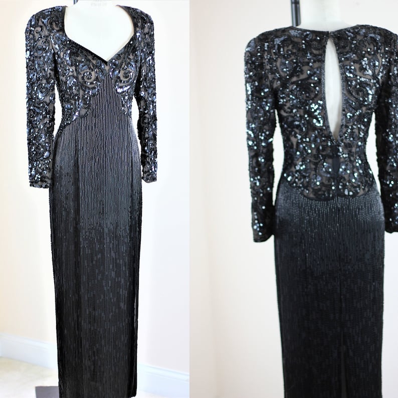 May include: A long-sleeved black sequined gown with a plunging neckline and a keyhole back. The gown is made of a shimmering fabric and has a fitted silhouette.