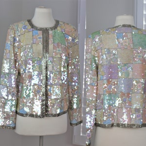 May include: A sequined jacket with a patchwork design in pastel colors. The jacket has a silver zipper and a silver trim around the edges.