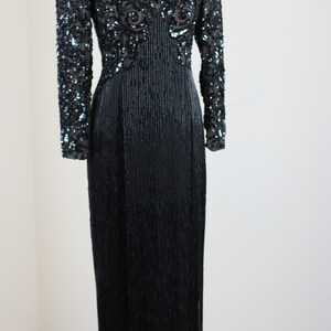 May include: A long-sleeved black sequined dress with a V-neckline and a fitted silhouette. The dress features intricate beading and sequins throughout, creating a glamorous and elegant look.
