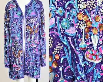 May include: A purple sequined jacket with a floral pattern in shades of blue, pink, and gold. The jacket has a long, open front and long sleeves.