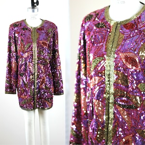May include: A sequined jacket with a floral pattern in shades of purple, pink, gold, and red. The jacket has a long, open front and long sleeves.
