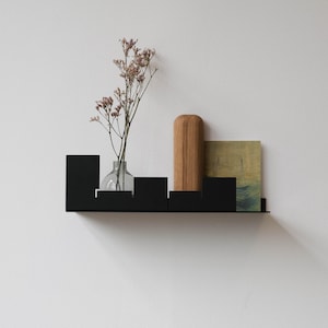 Schwebendes Regal aus schwarzem Metall: Minimalistisches Wanddekor aus gebogenem Stahl