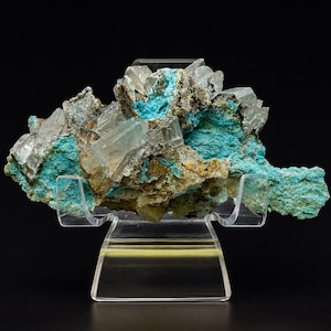 May include: A mineral specimen featuring a cluster of clear, crystalline formations atop a vibrant turquoise base. The specimen is displayed on a clear acrylic stand against a black backdrop, highlighting its natural beauty.