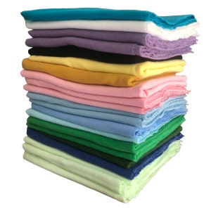 May include: A stack of 15 different colored fabric squares. The colors are turquoise, white, lavender, black, yellow, pink, light blue, dark blue, green, and light green.