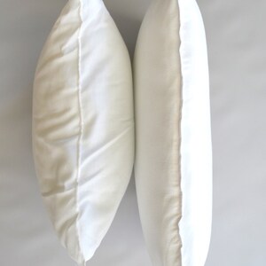May include: Two white pillowcases, side by side, with the seams facing out.