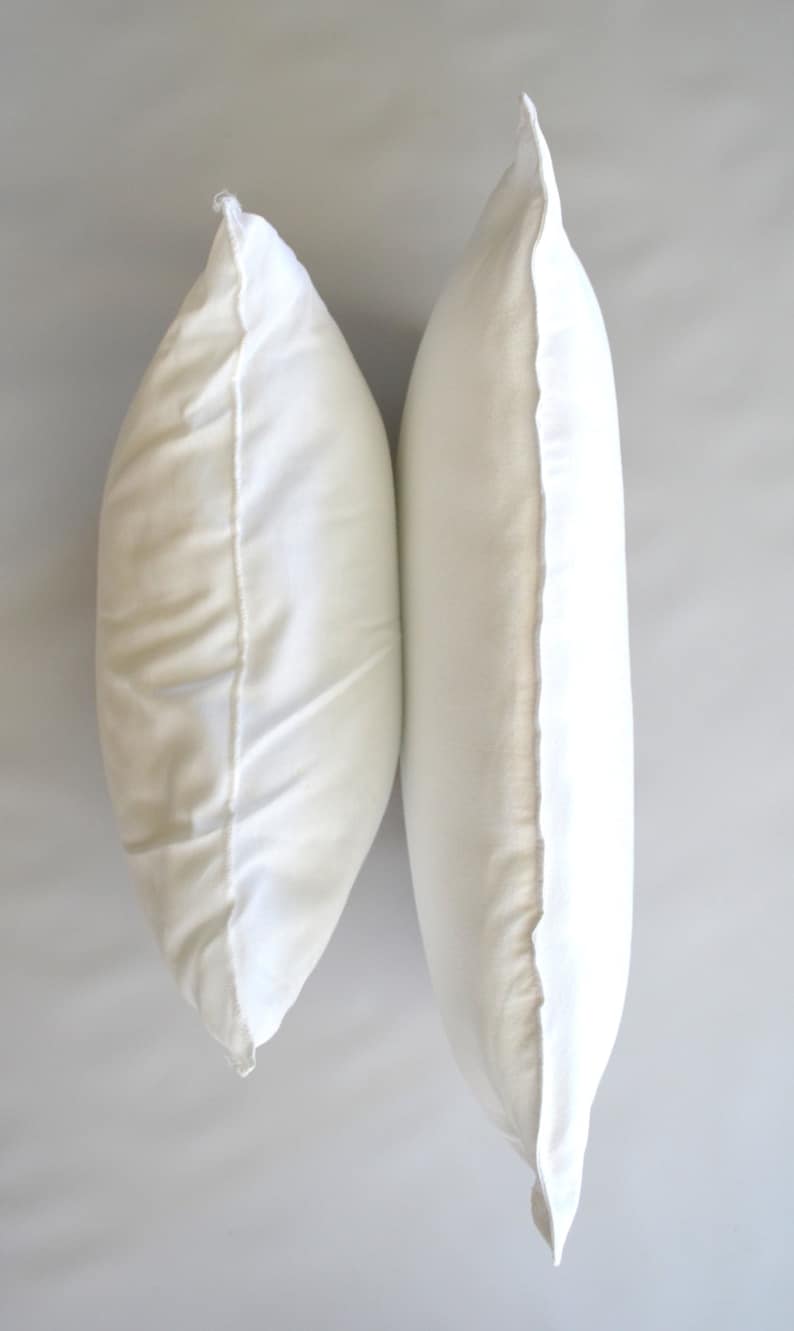 May include: Two white pillowcases, side by side, with the seams facing out.