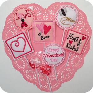 May include: Six Valentine's Day themed felt ornaments on sticks. The ornaments feature hearts, a ladybug, a butterfly, and the text "Love", "4 Ever", "Hugs & Kisses", "Happy Valentine's Day", and "Mimi".