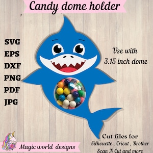 Könnte beinhalten: Ein blauer, haifischförmiger Bonbon-Kuppelhalter mit einem 8 cm großen Kuppel-Ausschnitt. Der Halter ist für die Verwendung mit Silhouette, Cricut, Brother, Scan N Cut und anderen Schneidemaschinen konzipiert. Das Bild enthält den Text "Candy dome holder", "Use with 3.15 inch dome", "Cut files for Silhouette, Cricut, Brother Scan N Cut and more", und "Magic world designs".