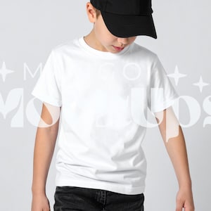 May include: A white crew neck t-shirt and black baseball cap. The t-shirt is plain and has short sleeves. The cap is black and has a curved brim. The person is wearing black jeans.