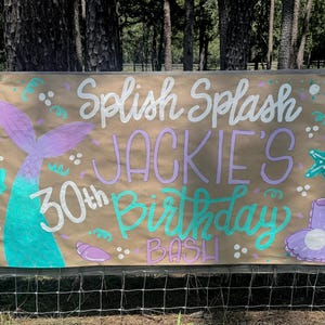 May include: A brown banner with the words "Splish Splash Jackie's 30th Birthday Bash" in white, purple, and teal. The banner features mermaid tail, seashell, and starfish illustrations.