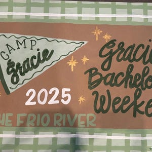 May include: A hand-painted banner with a brown background and a green and white checkered border. The banner reads "Camp Gracie" and "Gracie's Bachelorette Weekend 2025 The Frio River" in a whimsical font. Decorative elements include stars, drums, and a tent.