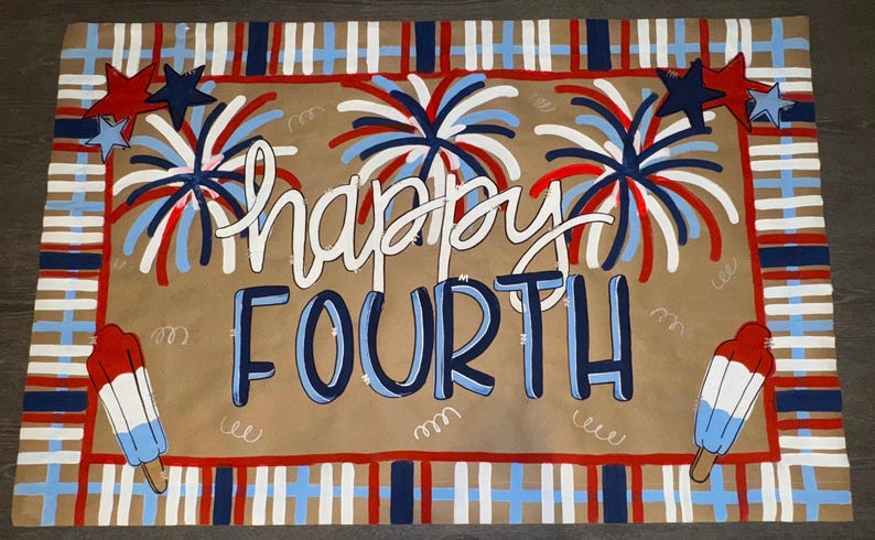May include: A rectangular, patriotic-themed mat with the words "happy FOURTH" in white and blue. The design includes fireworks, stars, and popsicle illustrations in red, white, and blue, with a plaid border.