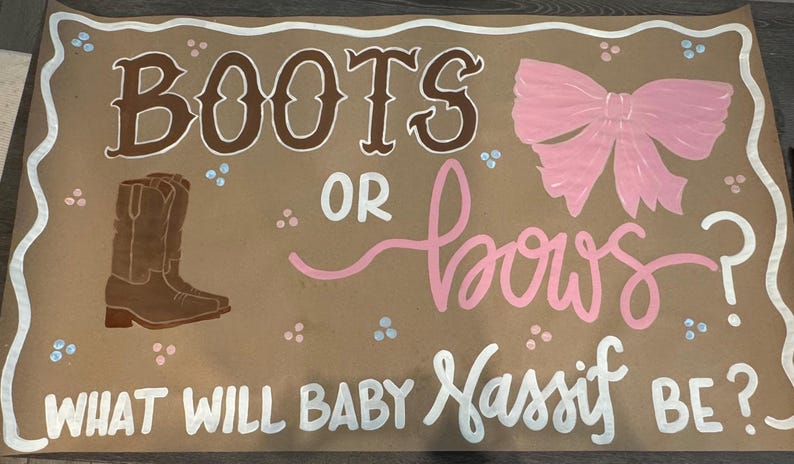 May include: A brown paper sign with the words "BOOTS OR BOWS?" in brown and pink lettering. The sign also includes a drawing of a cowboy boot and a pink bow. The text "WHAT WILL BABY Nassif BE?" is written in white.
