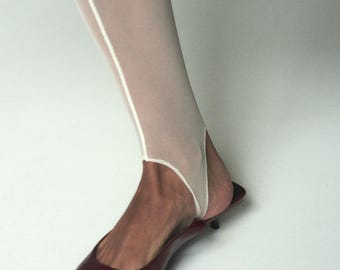 Puede incluir: Primer plano de una pierna y un pie con medias blancas con una raya blanca vertical y tacones de punta burdeos. Los tacones tienen un tacón bajo y fino.