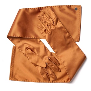May include: A pair of long, bronze-colored satin gloves and a matching sash. The gloves have a classic design with individual finger slots. The sash is long and rectangular, with a button detail at one end. The items are displayed on a white background.