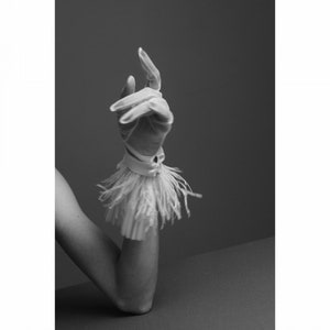 May include: A white glove featuring a wrist cuff adorned with long, delicate fringe detailing. The glove is constructed from a smooth, lightweight fabric that extends to cover the hand and fingers, with the fringe creating a textured effect.