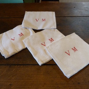 May include: Four white linen napkins with red embroidered initials "VM" on each.