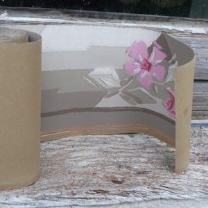 May include: Roll of vintage wallpaper with a floral pattern. The wallpaper is a light grey with a pink floral design. The wallpaper is rolled up and ready to be used.
