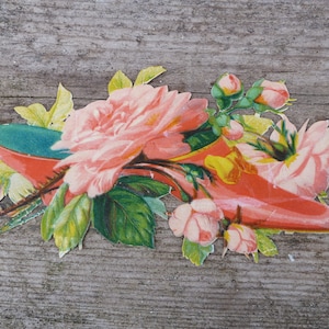 Könnte beinhalten: Ein Vintage-Papierschnitt einer rosa Schuh mit grünen und gelben Blumen und Blättern.